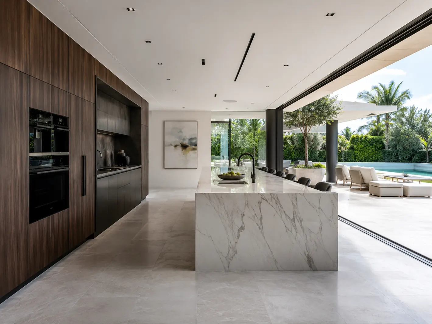 Cocina contemporánea con isla de mármol abierta al jardín y la piscina
